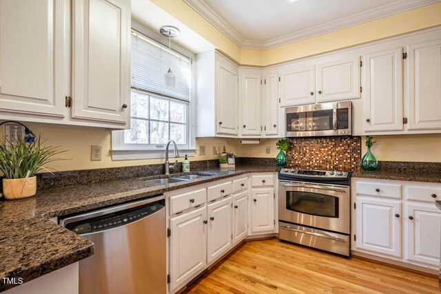 kitchen featuring white cabinets, stainless steel appliances, dark stone counters, and sink