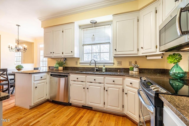 kitchen with white cabinets, stainless steel appliances, an inviting chandelier, and hanging light fixtures