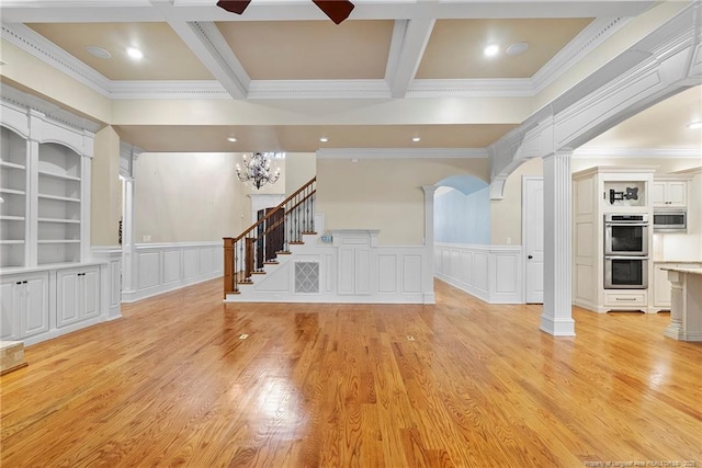 unfurnished living room featuring crown molding, built in features, beam ceiling, ornate columns, and light hardwood / wood-style floors