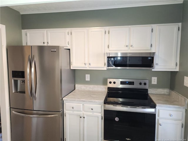 kitchen featuring white cabinets, stainless steel appliances, and ornamental molding