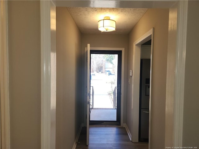 doorway to outside with dark hardwood / wood-style flooring and a textured ceiling