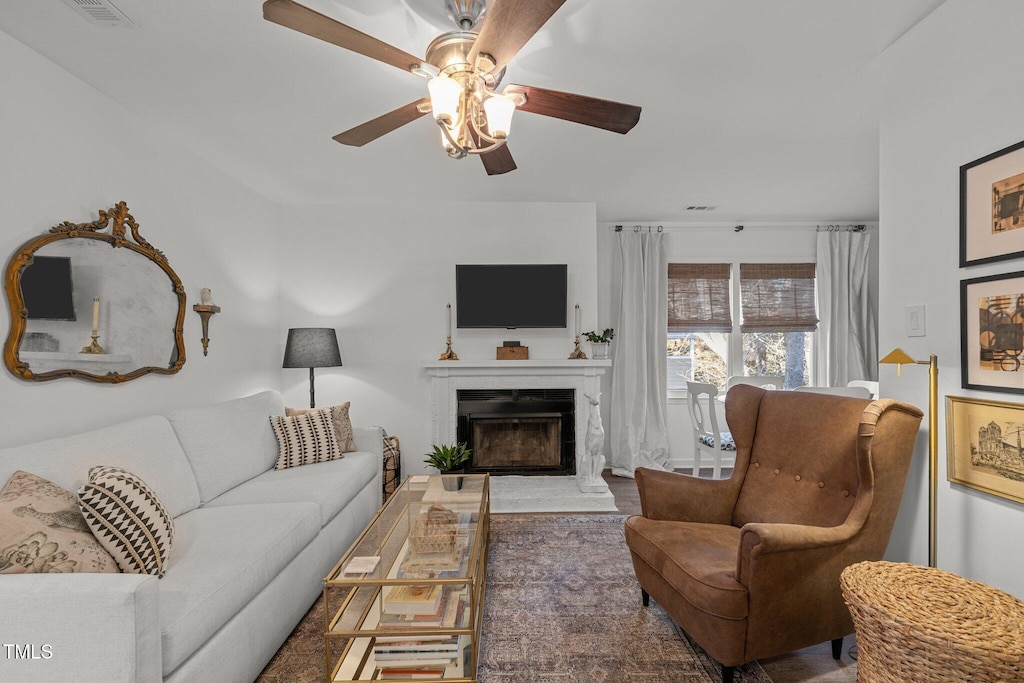 living room featuring a premium fireplace and ceiling fan