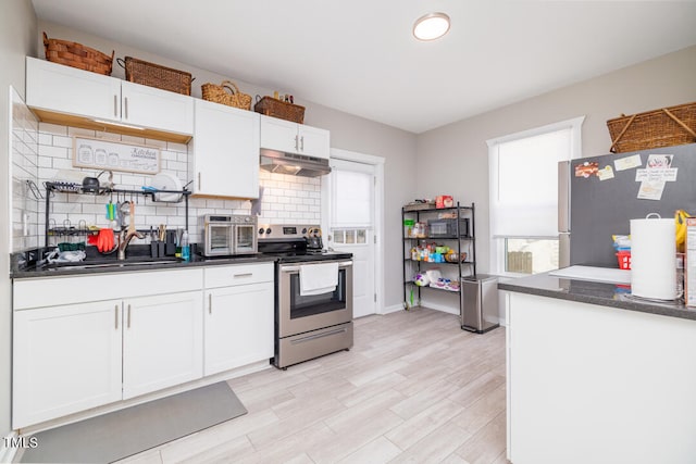 kitchen featuring light wood-type flooring, tasteful backsplash, stainless steel appliances, sink, and white cabinetry