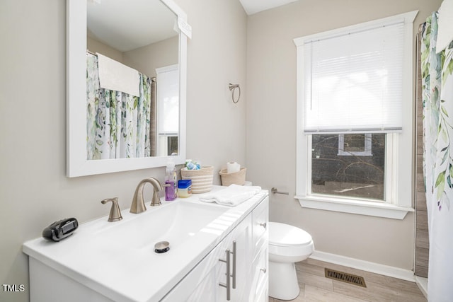 bathroom with vanity, a healthy amount of sunlight, toilet, and wood-type flooring