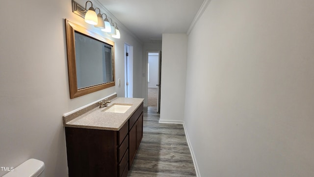 bathroom featuring vanity, hardwood / wood-style flooring, toilet, and ornamental molding