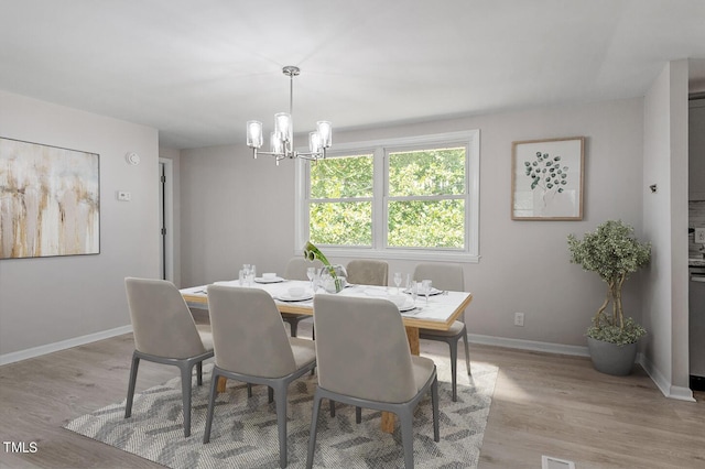 dining room featuring light wood-type flooring and a notable chandelier