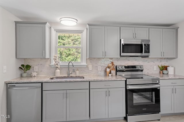 kitchen featuring appliances with stainless steel finishes, gray cabinetry, decorative backsplash, and sink