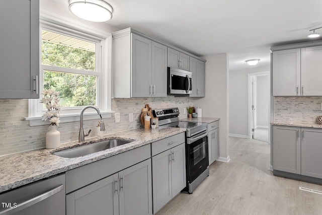 kitchen featuring sink, gray cabinets, stainless steel appliances, and light hardwood / wood-style floors