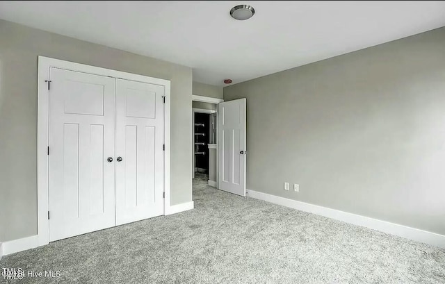 unfurnished bedroom with a closet and light colored carpet