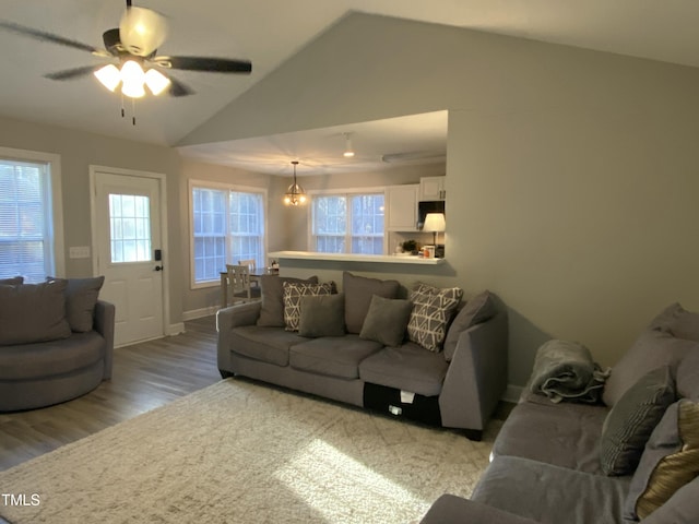 living room with lofted ceiling, ceiling fan with notable chandelier, and light hardwood / wood-style floors