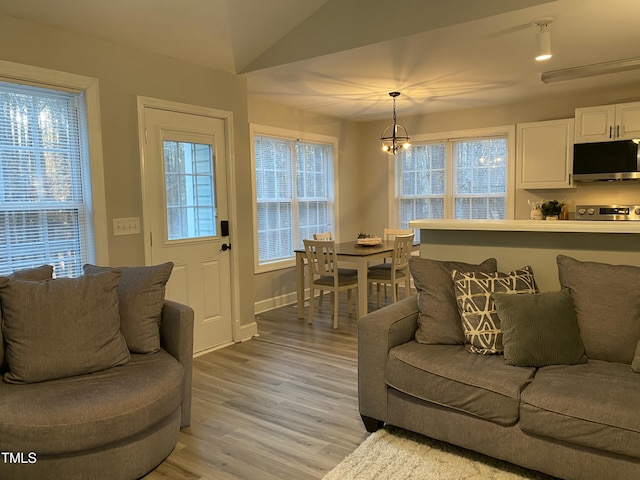 living room featuring lofted ceiling, light hardwood / wood-style flooring, and a chandelier