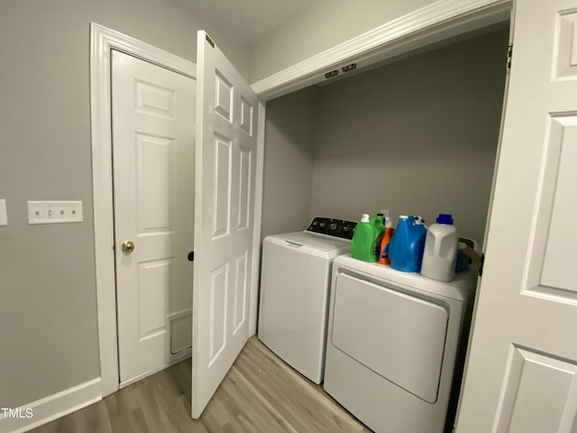 clothes washing area with independent washer and dryer and light wood-type flooring