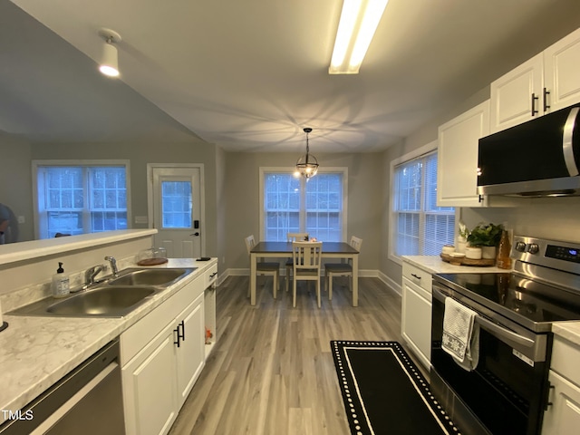 kitchen featuring pendant lighting, stainless steel appliances, light hardwood / wood-style floors, white cabinetry, and sink