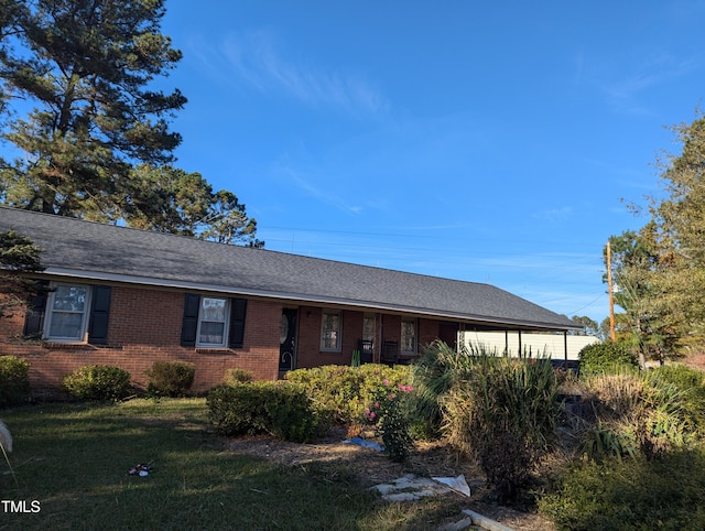 single story home featuring brick siding, a front lawn, and a shingled roof