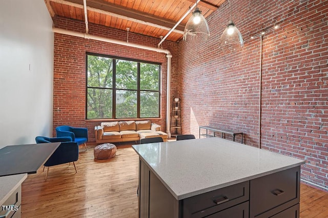 kitchen with brick wall, beamed ceiling, wooden ceiling, and hanging light fixtures