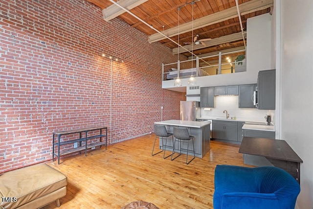 kitchen featuring a center island, stainless steel refrigerator, a high ceiling, gray cabinetry, and beam ceiling