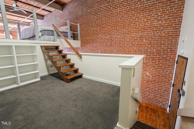 basement featuring brick wall, dark carpet, and wooden ceiling