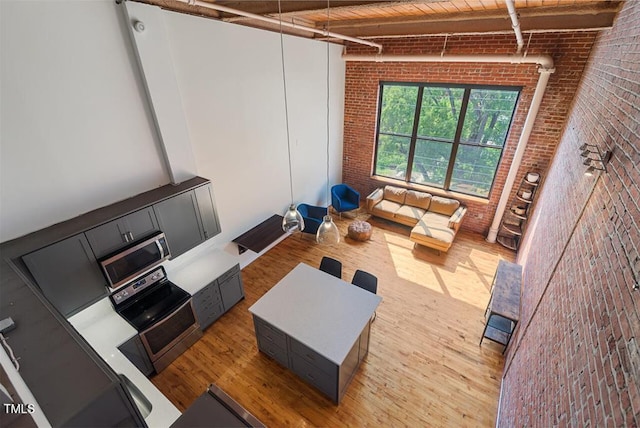 living room featuring brick wall, beam ceiling, light hardwood / wood-style flooring, and wood ceiling