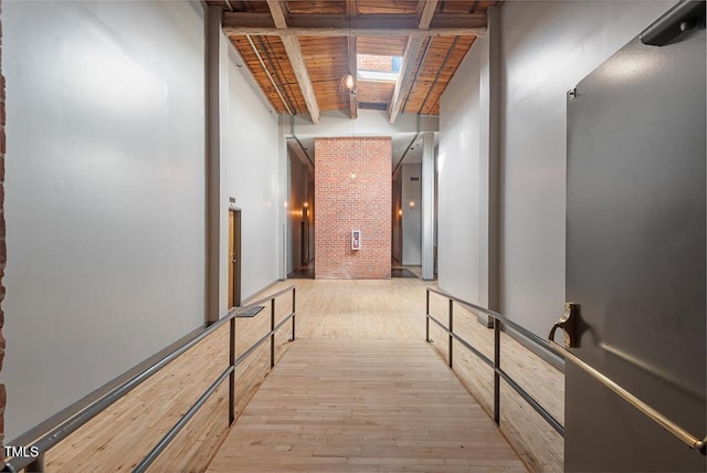 hall with light wood-type flooring, wooden ceiling, and beamed ceiling