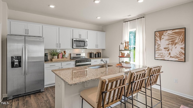 kitchen featuring sink, stainless steel appliances, white cabinetry, and an island with sink