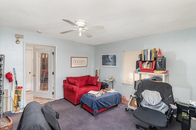 carpeted living room featuring ceiling fan and a textured ceiling