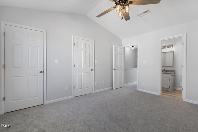 unfurnished bedroom featuring ceiling fan, vaulted ceiling, light colored carpet, and ensuite bathroom