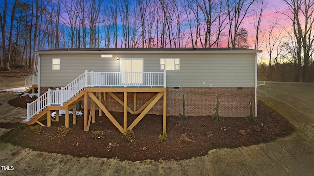 back house at dusk with a wooden deck