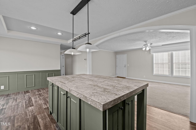 kitchen featuring ceiling fan, green cabinetry, decorative light fixtures, and a kitchen island