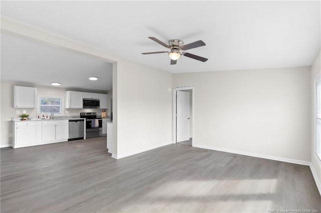 unfurnished living room with sink, hardwood / wood-style floors, and ceiling fan