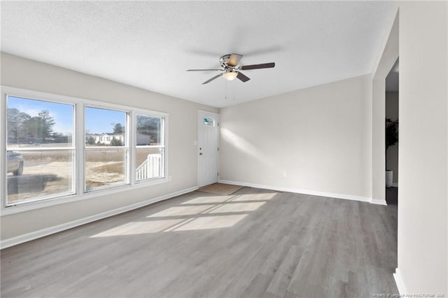 empty room featuring ceiling fan, a textured ceiling, and wood-type flooring