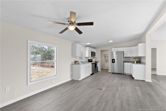 kitchen with appliances with stainless steel finishes, ceiling fan, light hardwood / wood-style floors, and white cabinets