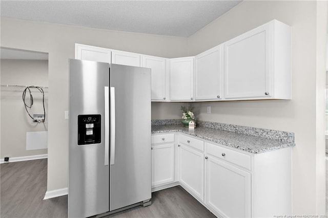 kitchen with light stone counters, a textured ceiling, stainless steel refrigerator with ice dispenser, light wood-type flooring, and white cabinets