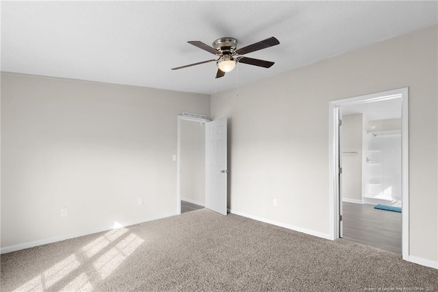 unfurnished bedroom with ceiling fan, a walk in closet, and dark carpet