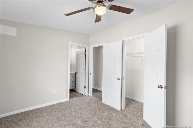 unfurnished bedroom featuring ensuite bathroom, ceiling fan, a closet, a walk in closet, and light colored carpet