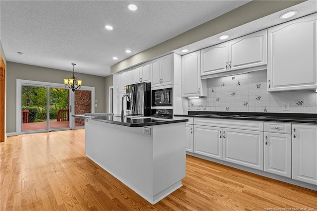 kitchen featuring white cabinets, an island with sink, decorative light fixtures, and black appliances