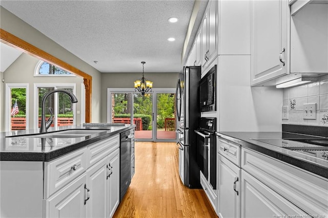 kitchen with a chandelier, a textured ceiling, white cabinetry, backsplash, and sink