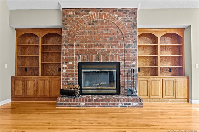 unfurnished living room featuring a fireplace, light hardwood / wood-style floors, and built in features