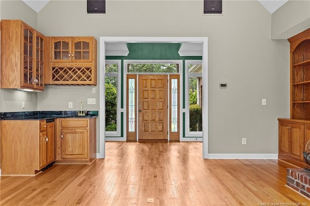 interior space featuring lofted ceiling, dark stone counters, light hardwood / wood-style flooring, and sink