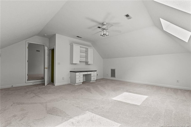 additional living space with ceiling fan, lofted ceiling with skylight, and light carpet