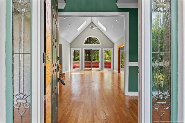 interior space with lofted ceiling with skylight, ceiling fan, and light hardwood / wood-style flooring