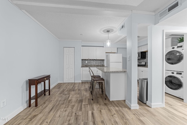 kitchen with stacked washer and clothes dryer, white cabinetry, hanging light fixtures, white refrigerator, and backsplash