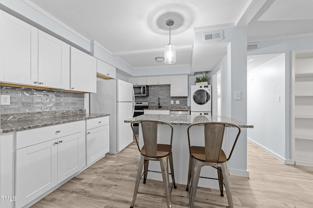 kitchen featuring white cabinetry, tasteful backsplash, decorative light fixtures, dark stone countertops, and stainless steel appliances