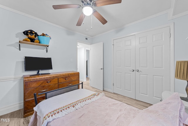 bedroom featuring ornamental molding, light wood-type flooring, ceiling fan, and a closet