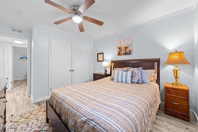 bedroom featuring ceiling fan, ornamental molding, a closet, and light hardwood / wood-style flooring