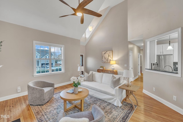 living room featuring high vaulted ceiling, light hardwood / wood-style floors, and ceiling fan