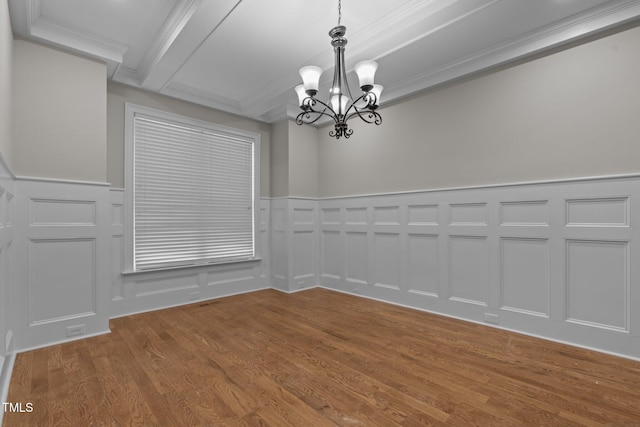 empty room featuring beam ceiling, ornamental molding, a chandelier, and hardwood / wood-style floors