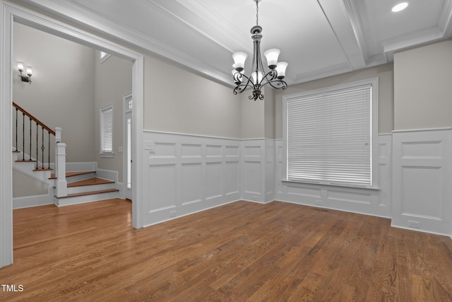 unfurnished dining area with a notable chandelier, ornamental molding, and wood-type flooring