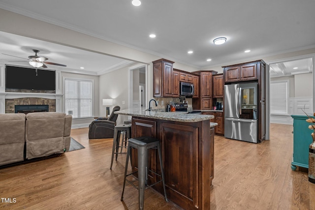 kitchen with kitchen peninsula, stainless steel appliances, crown molding, and a kitchen bar