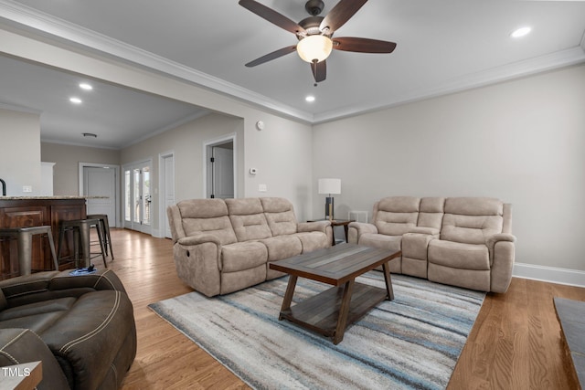 living room featuring ceiling fan, light hardwood / wood-style floors, and crown molding