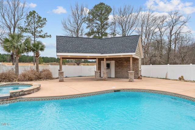 view of pool with a patio area, an outbuilding, and an in ground hot tub